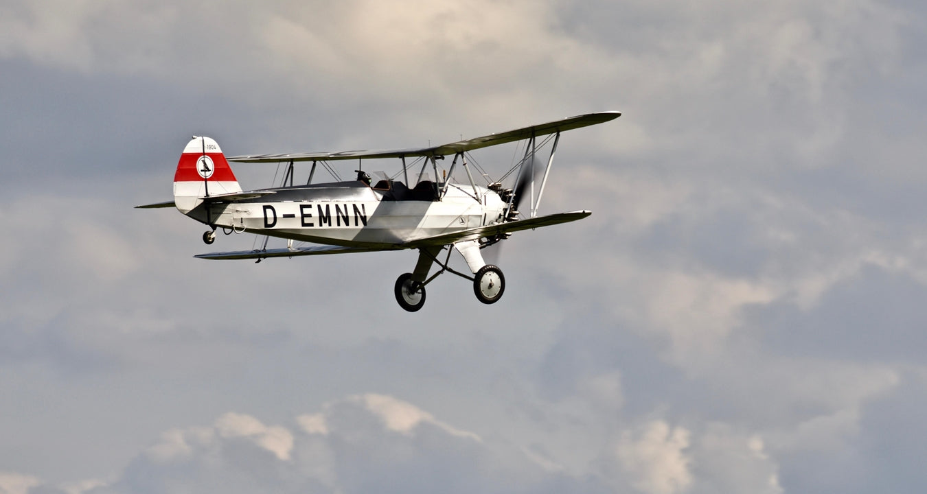 Vintage biplane flying against a cloudy sky
